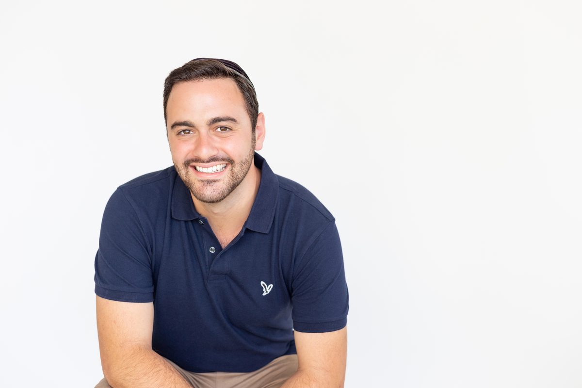 Abe Braha smiling, leaning in against a white background