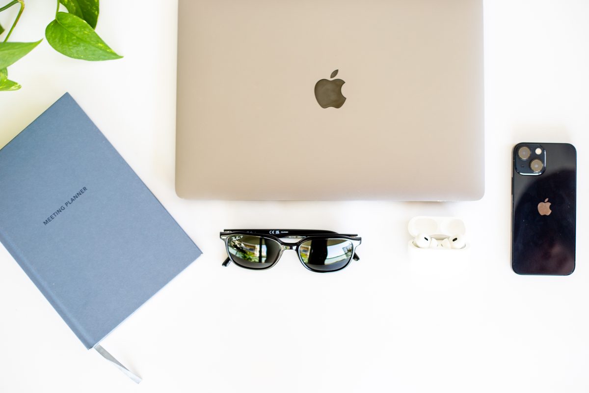 A notebook labelled Meeting Planner beside a laptop, sunglasses and a phone