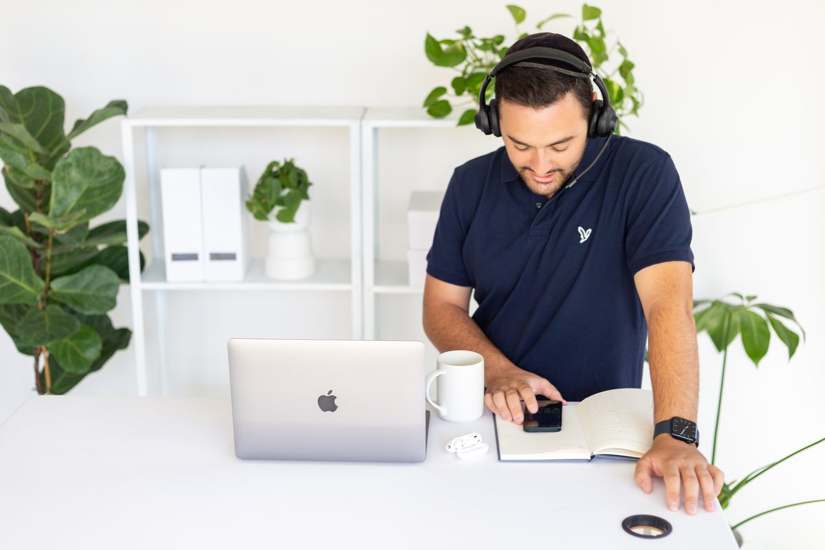 Abe Braha at a desk with a headset on, checking a phone