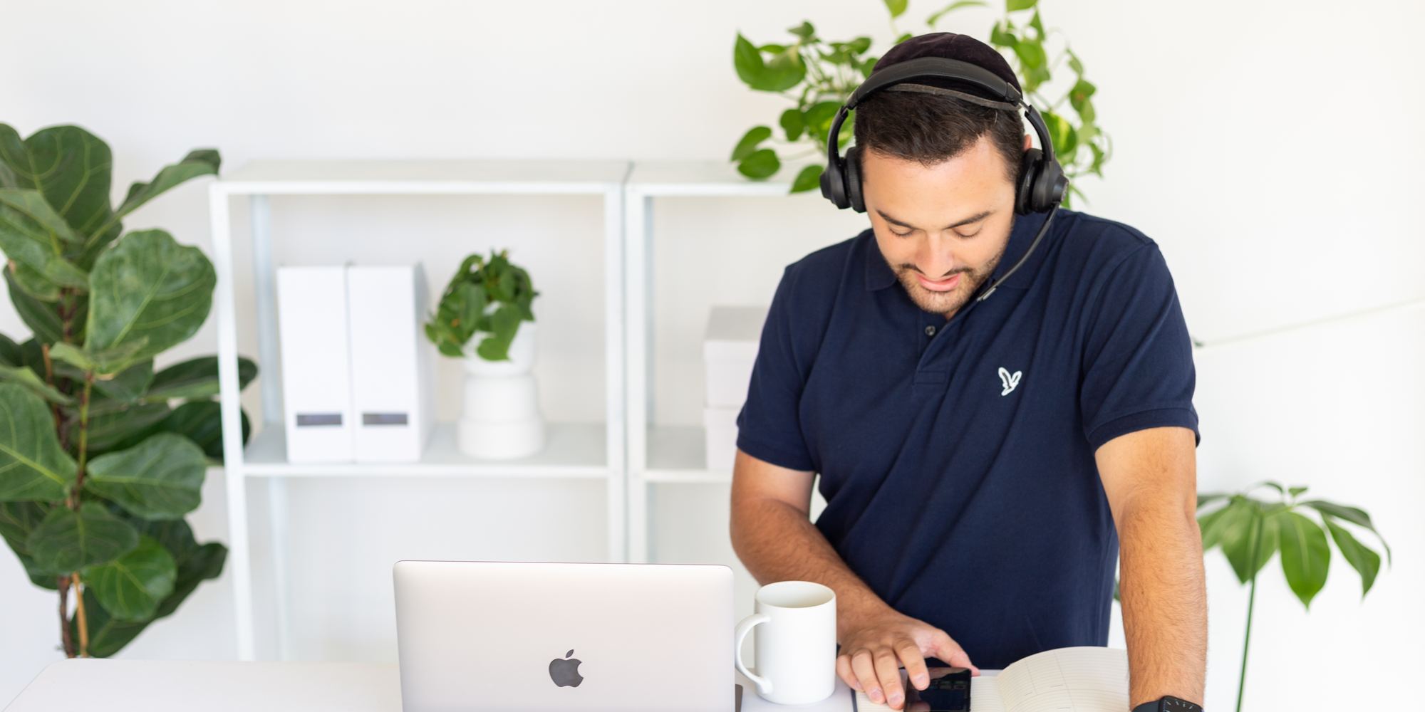 Abe Braha at a desk wearing a headset, checking a phone next to an open notebook